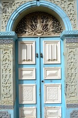 Obraz premium Traditional wooden blue and white aged Tunisian door with ornament in Kairouan Medina. Kairouan, Tunisia. 06/11/2019. 