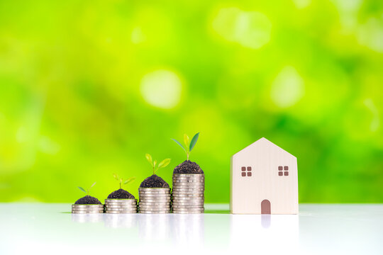 Stack of coins with plant growing and house with green nature background, Saving money for property investment concept