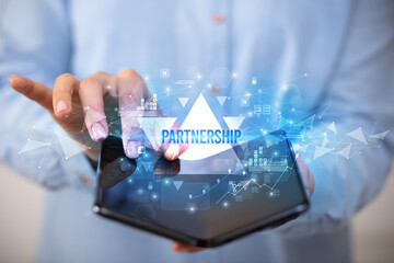 Businessman holding a foldable smartphone with PARTNERSHIP inscription, business concept