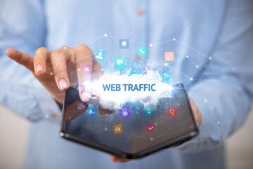 Businessman holding a foldable smartphone with WEB TRAFFIC inscription, technology concept