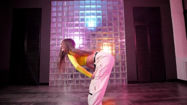 Beautiful young woman with long hair dancing hip hop, freestyle, dancehall in a choreographic studio. Gimbal shot