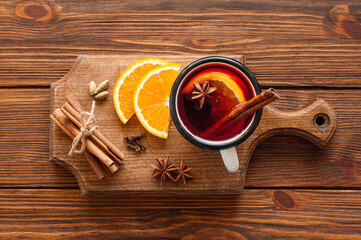 Christmas mulled red wine in glass mug with spices on wooden serving board. Christmas hot drink with ingredients: spices and fruits on wooden background. Top view. Lay out.