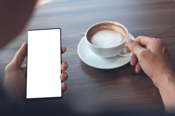 Mockup of man using blank screen mobile phone and drinking coffee in coffee shop