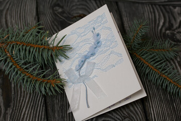 Greeting card among the fir branches. On black pine boards.