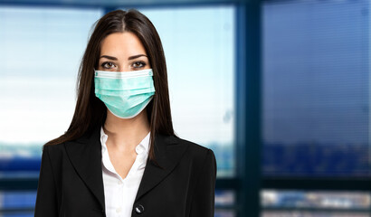 Smiling businesswoman wearing a mask in her office, coronavirus concept