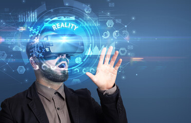 Businessman looking through Virtual Reality glasses with REALITY inscription, innovative technology concept