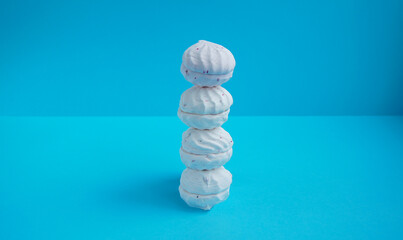 Colorful tasty marshmallow sculpture levitated on blue background. Minimalism concept