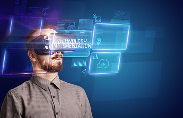 Businessman looking through Virtual Reality glasses with TECHNOLOGY IMPLEMENTATION inscription, new technology concept