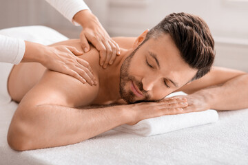 Closeup of relaxed man having body massage at spa