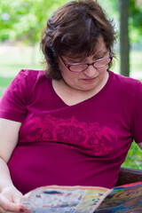 woman in glasses reading a newspaper in the park