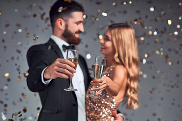 Selective focus of couple holding glasses of champagne and smiling isolated on grey background.