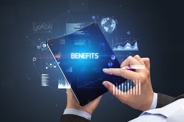Businessman holding a foldable smartphone with BENEFITS inscription, successful business concept
