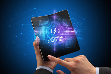 Businessman holding a foldable smartphone with COMPUTING inscription, new technology concept BACKWARD COMPATIBLE