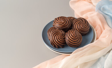 Traditional Russian vanilla marshmallows in chocolate glaze in blue and white plates on gray background