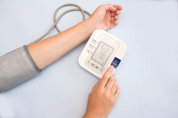 Pressure measurement. A woman takes care of her health by checking her blood pressure and pulse on her hand. Measure your blood pressure and pulse yourself. blue background