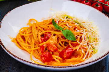 Traditional Italian pasta with tomato, parmesan cheese and basil on white plate.