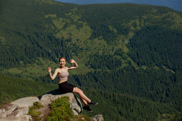 Naklejka premium A woman sits on the edge of the cliff and looking at the sun valley and mountains