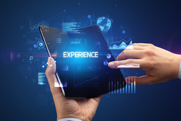 Businessman holding a foldable smartphone with EXPERIENCE inscription, successful business concept