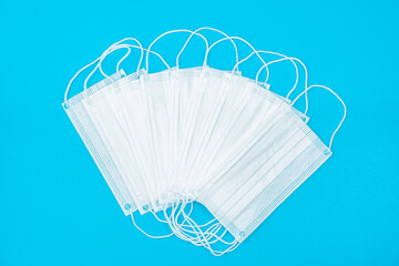White medical mask isolated on blue background. Medical mask protection against pollution, virus, flu, coughing and coronavirus. Health care and surgical concept.