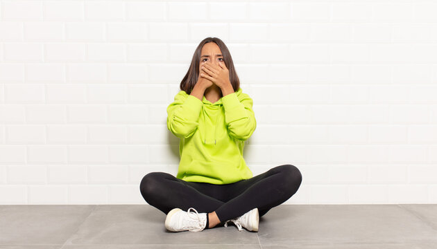 hispanic woman covering mouth with hands with a shocked, surprised expression, keeping a secret or saying oops
