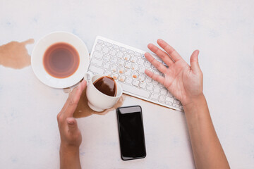 A Cup of coffee spilled on the keyboard. Pour coffee on the keyboard in the office. Not good morning at work, spilled coffee