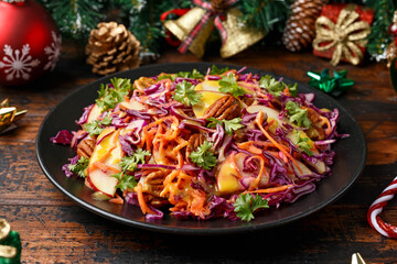 Christmas Red Cabbage, carrots, apples and pecan nuts Salad with decoration, gifts, green tree branch on wooden rustic table