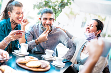 Friends having fun eating croissants at coffee house - Young people laughing together at restaurant cafeteria - New normal lifestyle concept with happy men and women at cafe bar - Bright azure filter