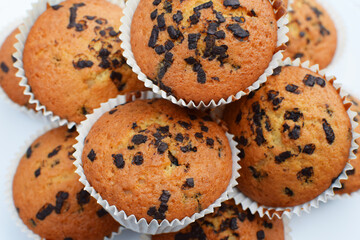Chocolate - sprinkled homemade tasty muffins or cupcakes on white background closeup selective focus view.
