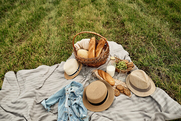 Picnic basket with fruit and bakery. Picnic on the grass, basket, hats. Outdoor lunch summer rest...
