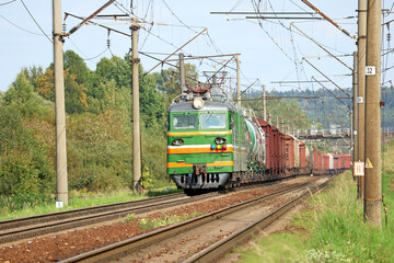 Fototapeta na wymiar powerful electric locomotive with a freight train arrives at the railway station