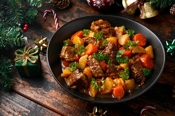 Christmas Beef Stew with decoration, gifts, green tree branch on wooden rustic table - obrazy, fototapety, plakaty
