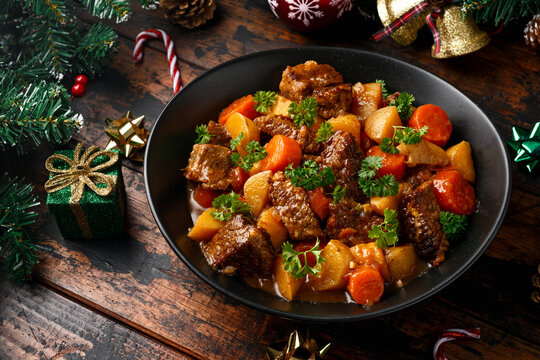 Christmas Beef Stew with decoration, gifts, green tree branch on wooden rustic table