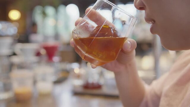 close-up female hand hold brew coffee dink glass with ice  in coffeeshop background
