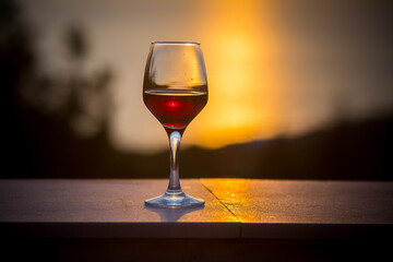 Beautiful scene with wine glass standing alone on natural sunset sky