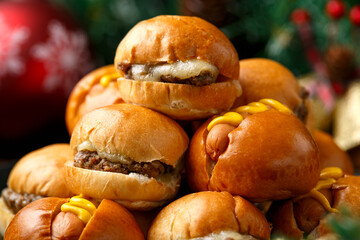 Christmas mini hamburgers, burger and hot dogs with decoration, gifts, green tree branch on wooden rustic table