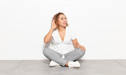 middle age woman looking serious and curious, listening, trying to hear a secret conversation or...