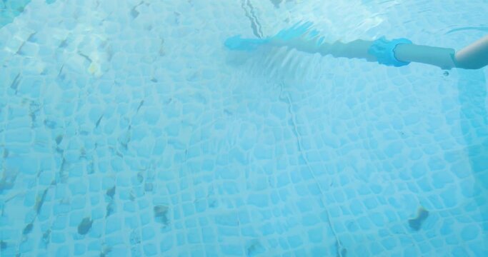 cleaning swimming pool with a special brush.