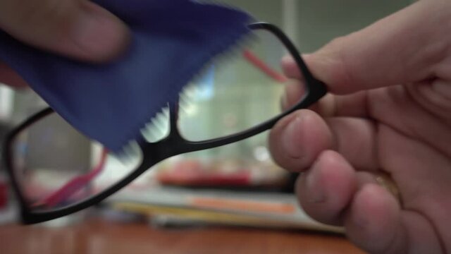 Close up horizontal video of person cleaning his glasses. Shallow depth of field. Eye wear care concept for clear vision.