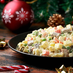 Christmas and New year Olivier salad, traditional Russian food with decoration, gifts, green tree branch on wooden rustic table