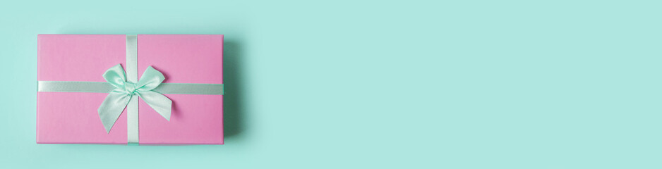 Christmas New Year birthday valentine celebration present concept. Simply minimal design pink gift box isolated on blue pastel background. Flat lay top view copy space, banner