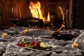 Red wine at fireplace with strawberries and chocolate
