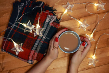 Fototapeta na wymiar women's hands warm on a mug of hot chocolate milk