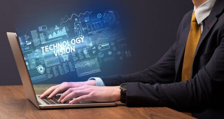 Businessman working on laptop with TECHNOLOGY VISION inscription, cyber technology concept