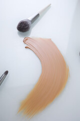 a smear of makeup Foundation and brush on a white background