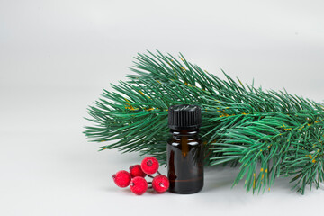 small brown cosmetic bottle with christmas tree branches and red christmas stuff on light background