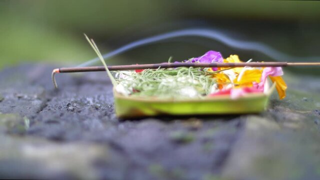 Burning incense stick placed on balinese offering