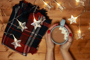 women's hands warm on a mug of hot chocolate milk with marshmallows