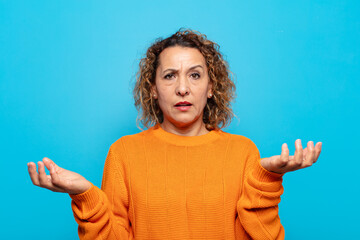middle age woman shrugging with a dumb, crazy, confused, puzzled expression, feeling annoyed and...