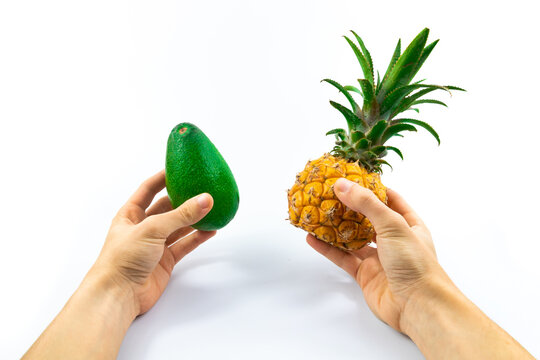 Small Baby Pineapple And Avocado In Man's Hands Size Comparison On White Isolated Background