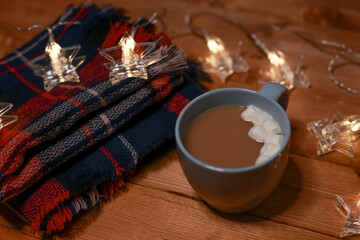 a mug of hot chocolate with marshmallows on the table and lights